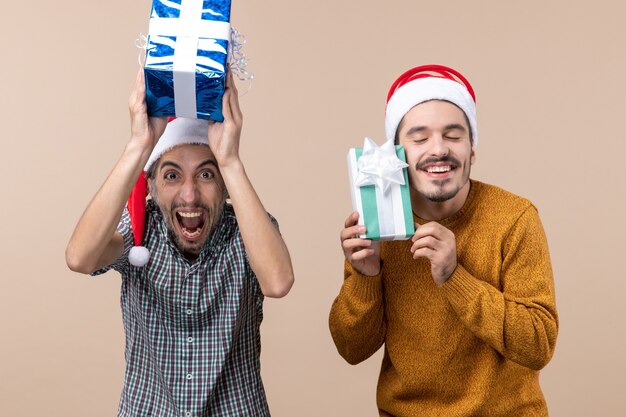 Vue de face deux hommes heureux tenant des cadeaux de Noël