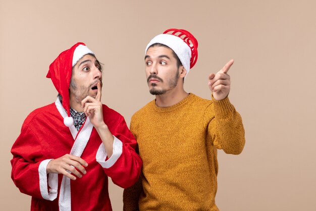 Vue de face deux hommes regardant quelque part avec intérêt sur fond isolé beige