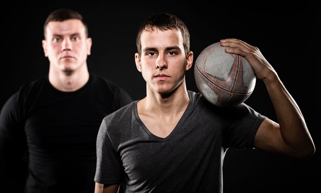 Vue de face de deux joueurs de rugby masculins posant avec ballon