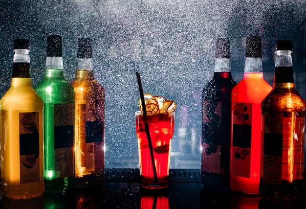 Vue de face différentes boissons colorées à l'intérieur des bouteilles