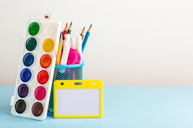 Vue de face différents crayons colorés avec des peintures sur un bureau bleu