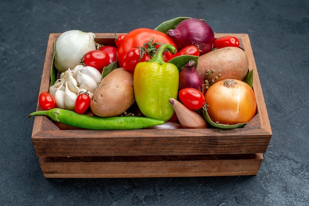 Vue de face différents légumes frais sur table sombre salade fraîche de légumes mûrs