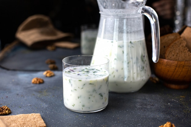 Une vue de face dovga poivrée salée fraîche comme boisson avec des verts sur le fond gris liquide soupe