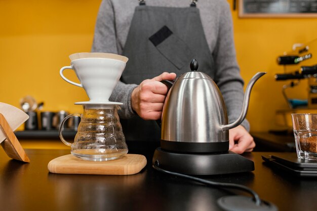 Vue de face du barista mâle tenant une bouilloire