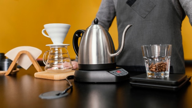 Vue de face du barista masculin préparer le café avec bouilloire et filtre