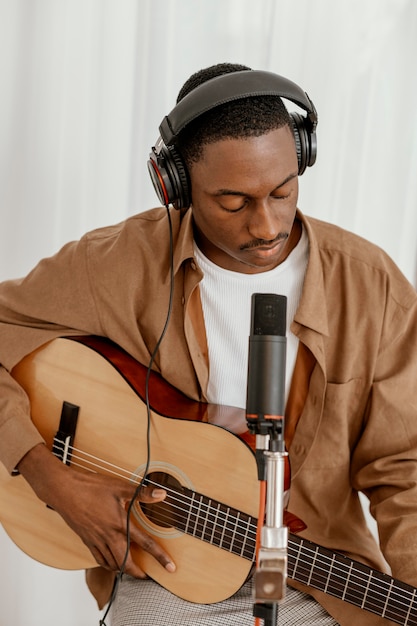 Vue de face du beau musicien masculin à la maison à jouer de la guitare