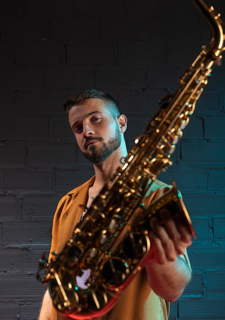 Photo gratuite vue de face du beau musicien masculin tenant saxophone