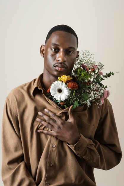 Vue de face du bel homme posant avec bouquet de fleurs
