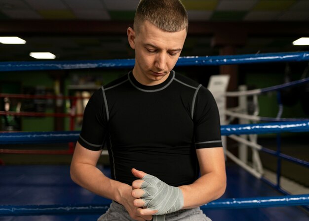 Vue de face du boxeur masculin enveloppant ses mains avant la formation