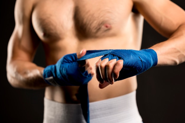 Vue de face du boxeur masculin mettant sur la protection des mains