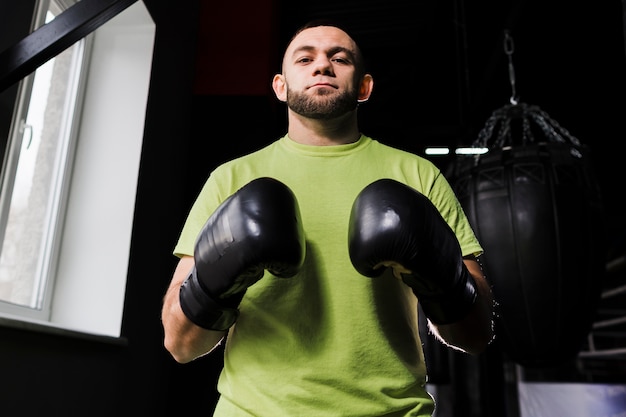 Vue de face du boxeur masculin portant des gants de protection et un t-shirt