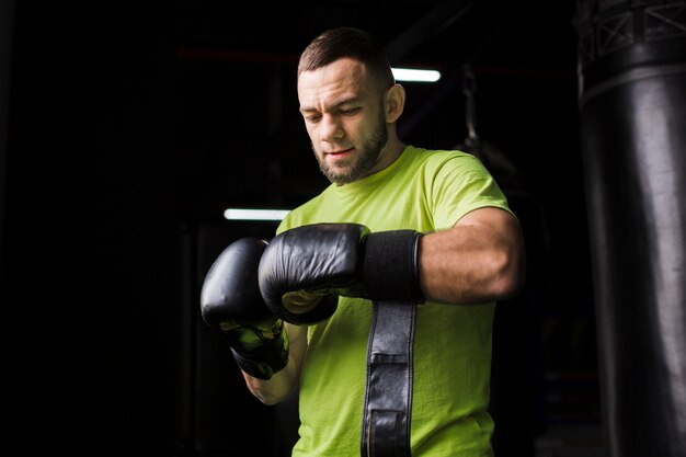 Vue de face du boxeur masculin en t-shirt avec des gants de protection