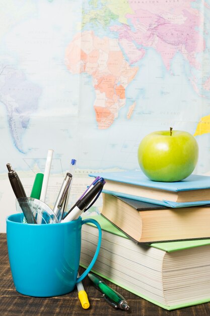 Vue de face du bureau avec des fournitures scolaires et une pomme