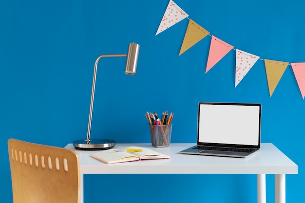 Photo gratuite vue de face du bureau pour enfants avec des crayons colorés et un ordinateur portable