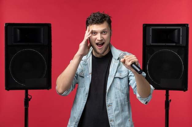 Vue de face du chanteur sur scène avec système stéréo sur le mur rouge