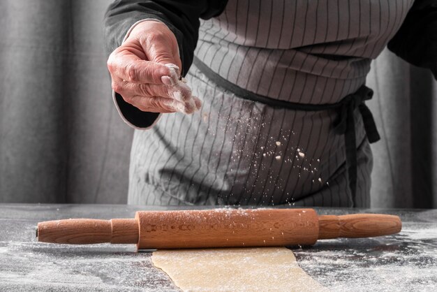 Vue de face du chef féminin à l'aide de farine pour rouler la pâte