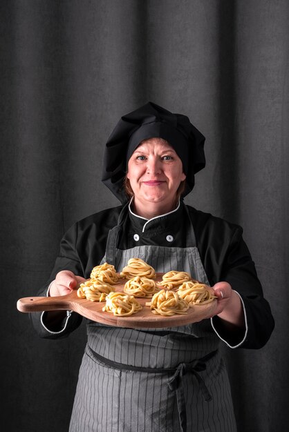 Vue de face du chef féminin présentant des pâtes