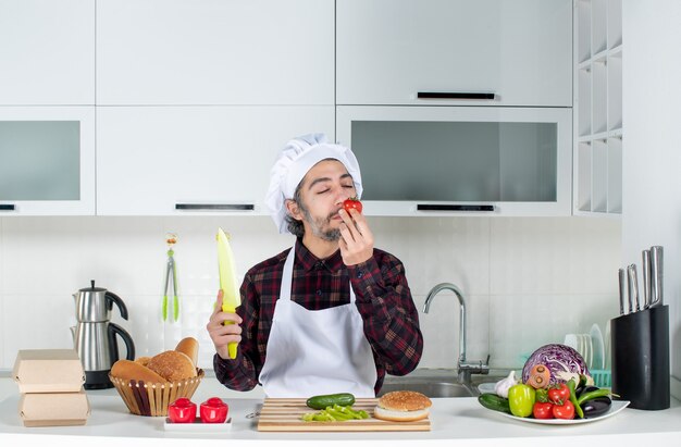 Vue de face du chef masculin sentant la tomate dans la cuisine