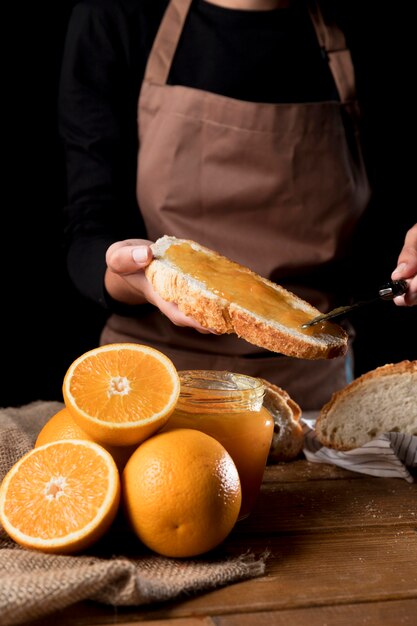 Vue de face du chef répandre la marmelade d'orange sur le pain