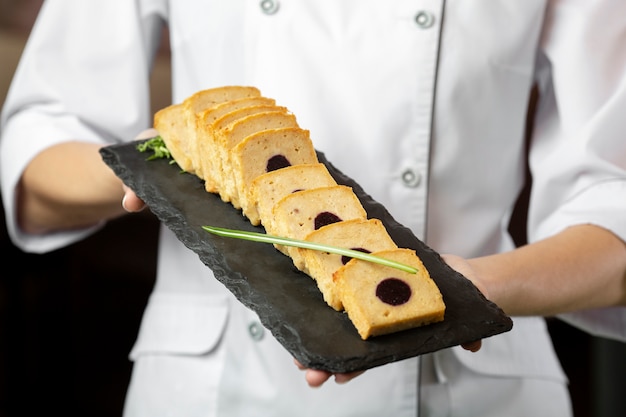 Vue de face du chef tenant une assiette de nourriture délicieuse