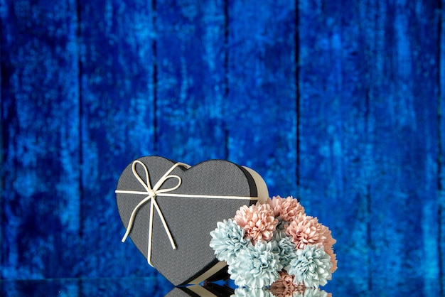 Vue de face du coffret coeur avec des fleurs colorées de couverture noire sur l'espace libre de fond en bois bleu