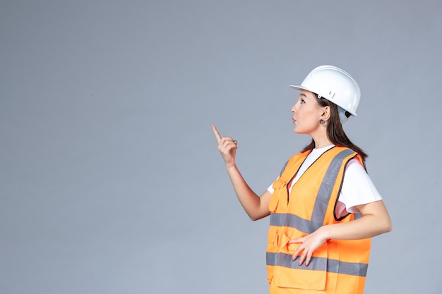 Vue de face du constructeur féminin en uniforme sur mur blanc