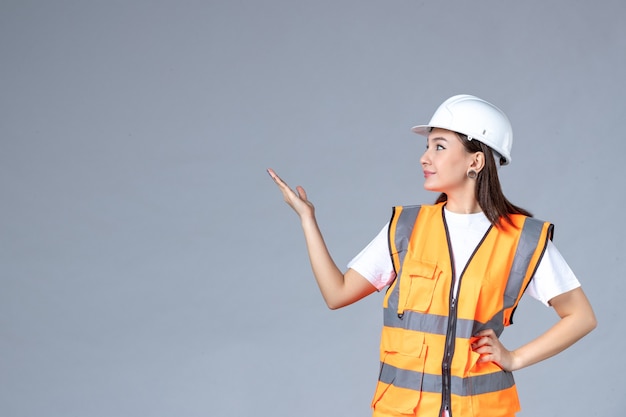 Vue de face du constructeur féminin en uniforme sur un mur gris