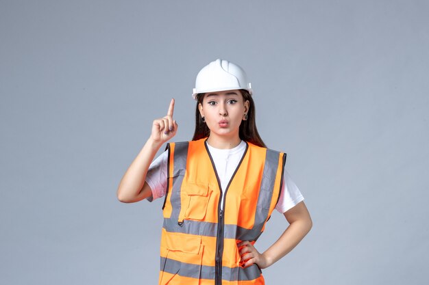 Vue de face du constructeur féminin en uniforme sur un mur gris