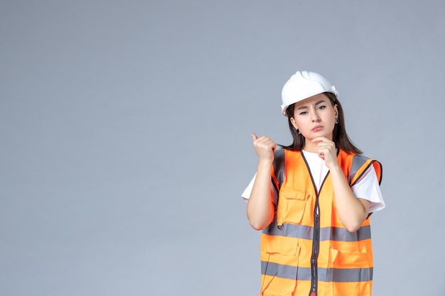 Vue de face du constructeur féminin en uniforme sur un mur gris