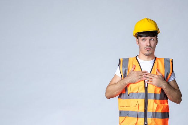 vue de face du constructeur masculin en uniforme et casque jaune sur mur blanc