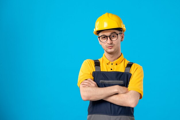 Vue de face du constructeur masculin en uniforme et casque sur mur bleu