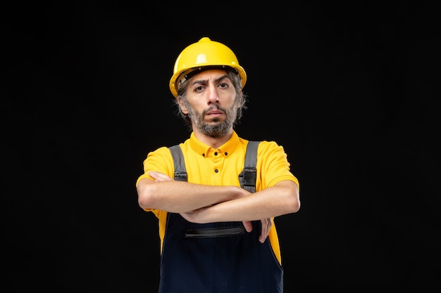Photo gratuite vue de face du constructeur masculin en uniforme jaune sur le mur noir