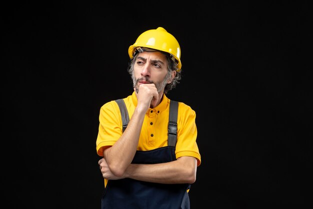 Vue de face du constructeur masculin en uniforme jaune sur le mur noir