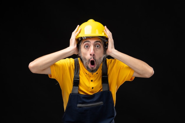 Vue de face du constructeur masculin en uniforme jaune sur le mur noir