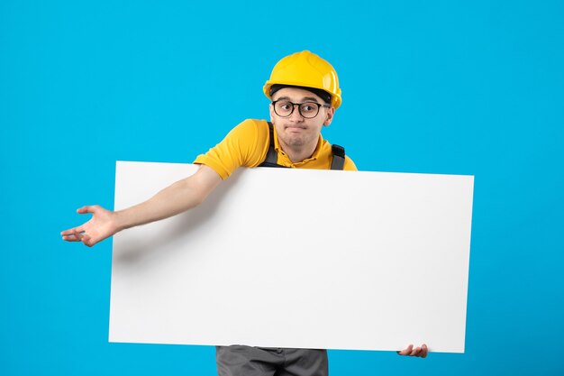 Vue de face du constructeur masculin en uniforme jaune avec plan sur bleu