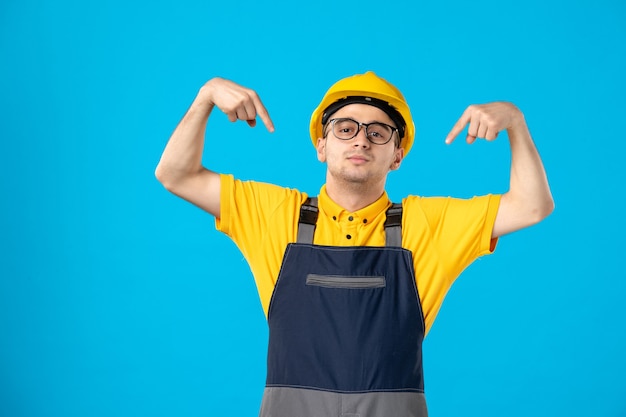 Vue de face du constructeur masculin en uniforme sur mur bleu