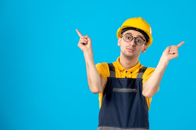 Photo gratuite vue de face du constructeur masculin en uniforme sur mur bleu