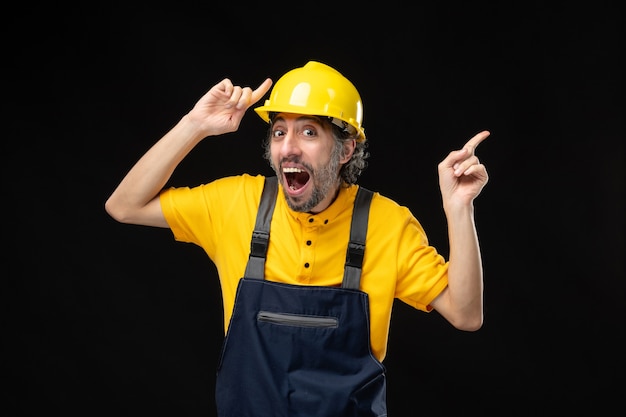 Photo gratuite vue de face du constructeur masculin en uniforme sur le mur noir