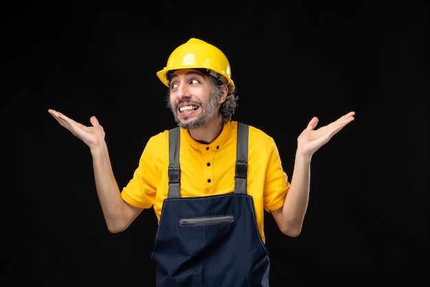 Vue de face du constructeur masculin en uniforme sur le mur noir