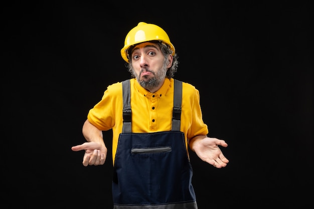 Photo gratuite vue de face du constructeur masculin en uniforme sur le mur noir