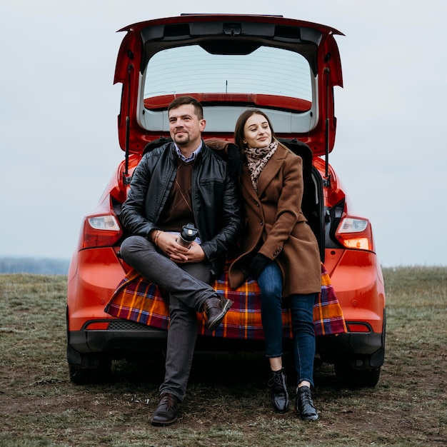 Vue de face du couple assis à l'extérieur dans le coffre de la voiture