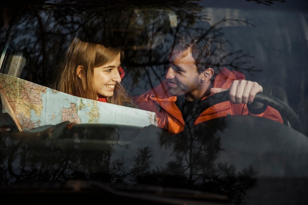 Photo gratuite vue de face du couple avec carte à l'intérieur de la voiture partant en road trip