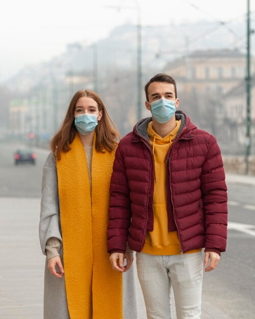 Vue de face du couple posant avec des masques médicaux