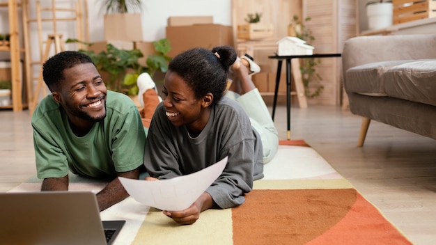 Photo gratuite vue de face du couple souriant faisant des plans pour redécorer la maison avec un ordinateur portable