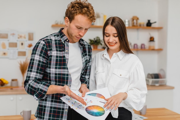 Vue de face du couple souriant faisant des plans pour rénover la maison