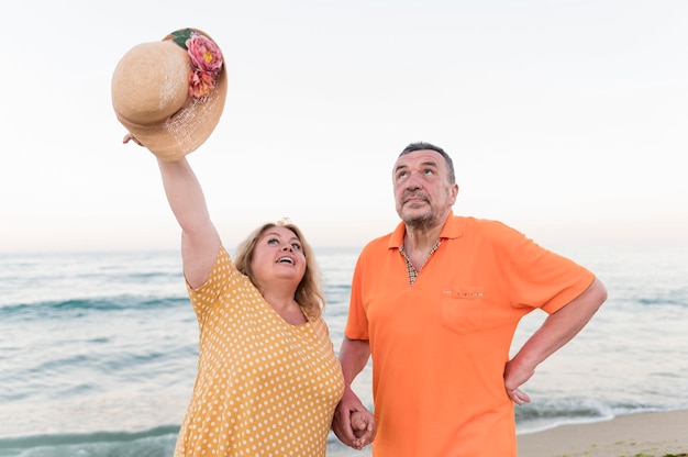 Vue de face du couple de touristes aînés à la plage