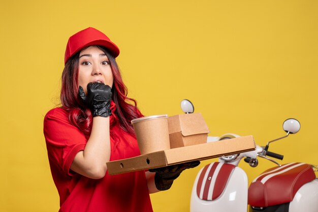 Vue de face du courrier féminin avec livraison de nourriture et de dessert sur mur jaune