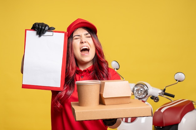 Vue de face du courrier féminin avec livraison de nourriture et de dessert sur mur jaune