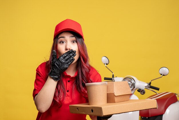 Vue de face du courrier féminin avec livraison de nourriture et de dessert sur mur jaune