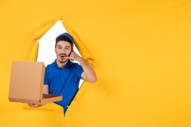 Photo gratuite vue de face du courrier masculin tenant une boîte à pizza ouverte sur un espace jaune